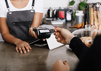 Restaurant worker taking card payment from a customer over counter